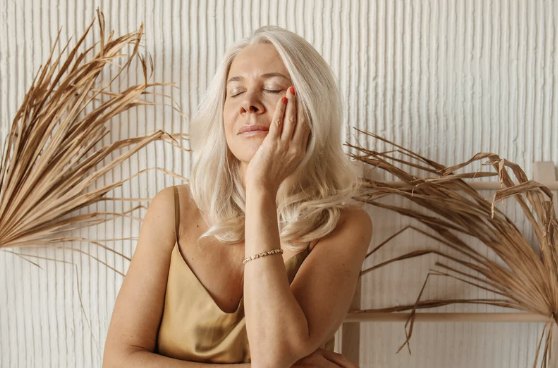 A woman resting a hand on her cheek, eyes closed